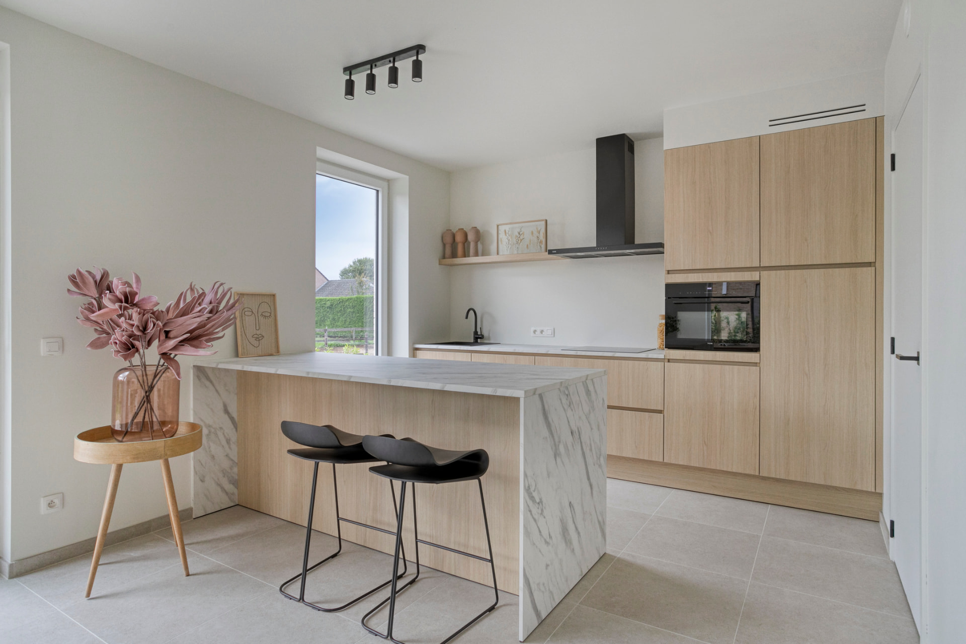 Open keuken met marmeren eiland en twee barkrukken in de modelwoning